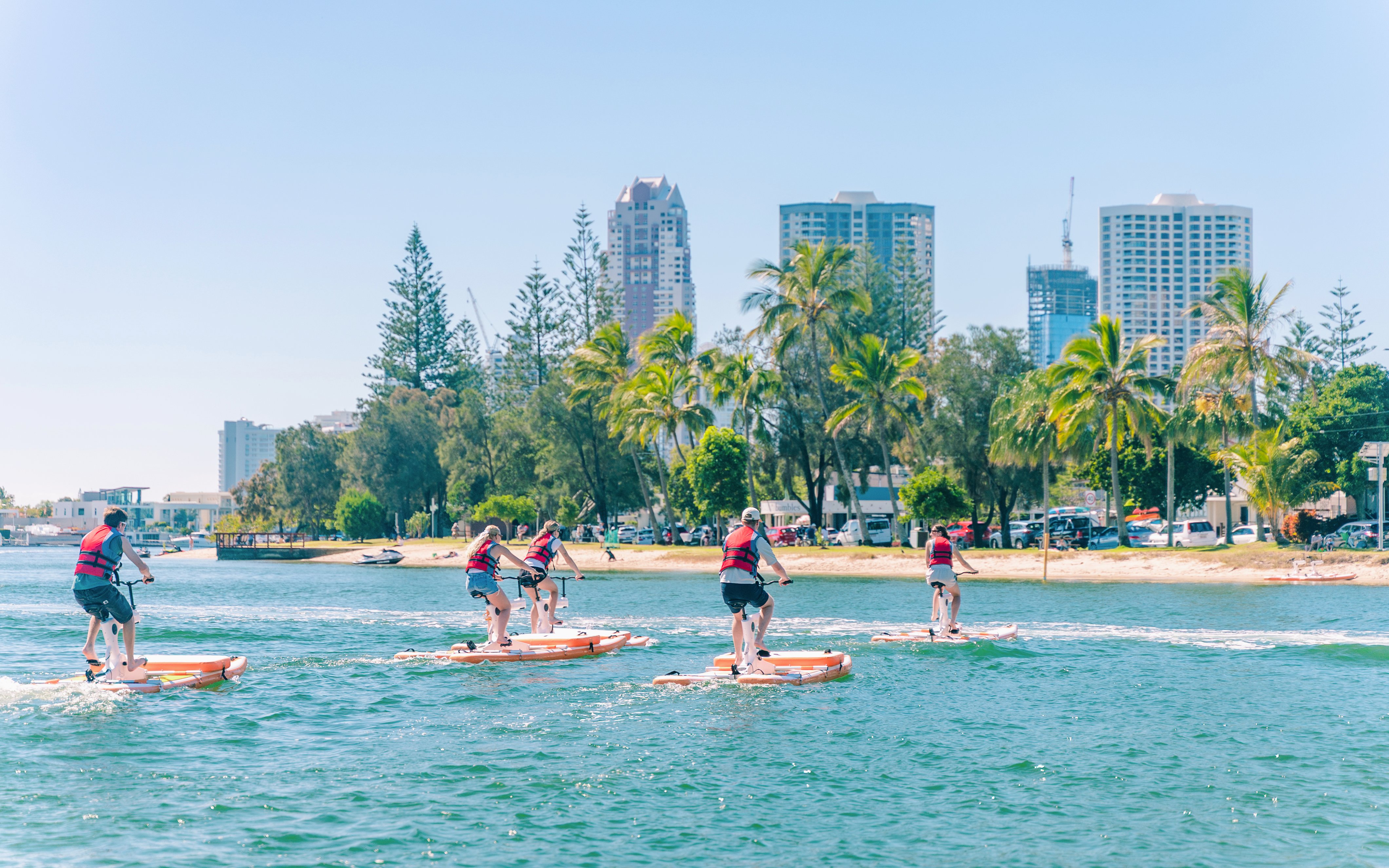 Tourists riding waterbikes on the Gold Coast with city skyline in the background.