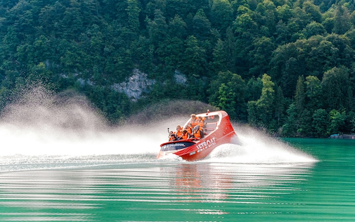 Jetboat speeding on Lake Brienz with forested hills in the background.