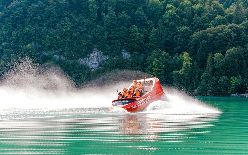 Jetboat speeding on Lake Brienz with forested hills in the background.
