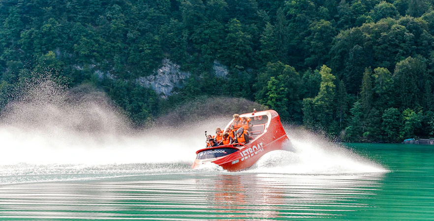 Jetboat speeding on Lake Brienz with forested hills in the background.