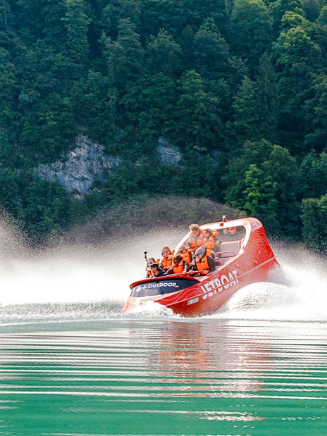 Jetboat speeding on Lake Brienz with forested hills in the background.
