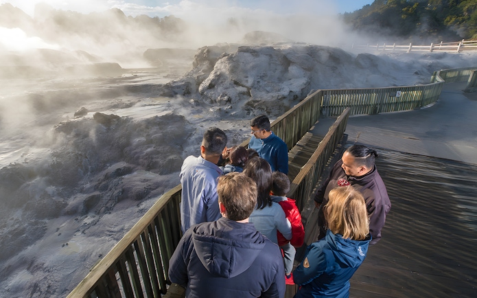 Visitors observing geothermal activity at Te Puia, Rotorua during guided tour from Auckland.