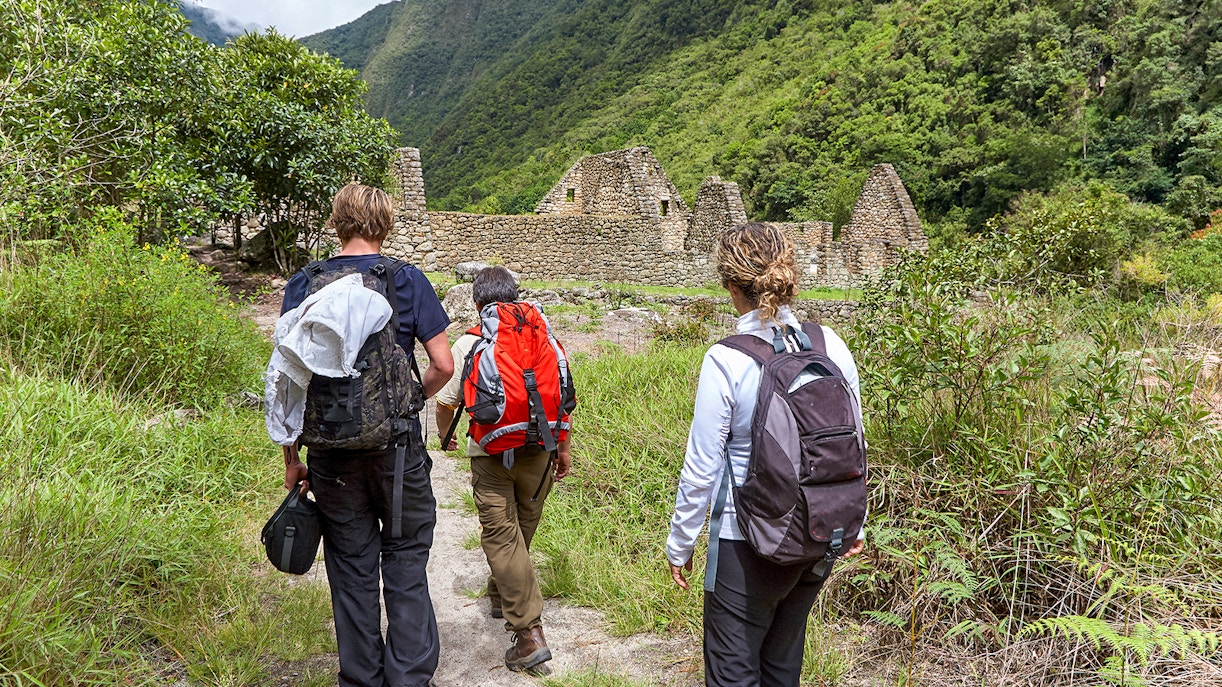 Hikers on the Inca Trail approaching Machu Picchu, Peru, surrounded by lush mountains.