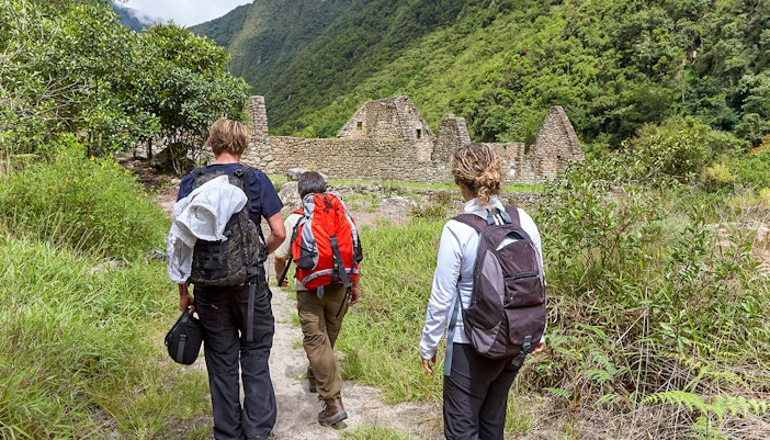 Hikers on Inca Trail approaching ancient ruins near Machu Picchu.