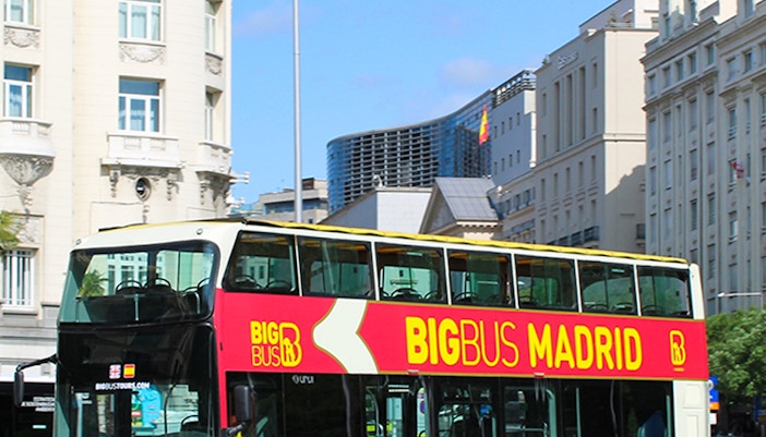 Open-top double-decker bus touring past the Royal Palace in Madrid, Spain.