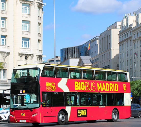 Big Bus Madrid tour bus in city center with historic buildings in background.