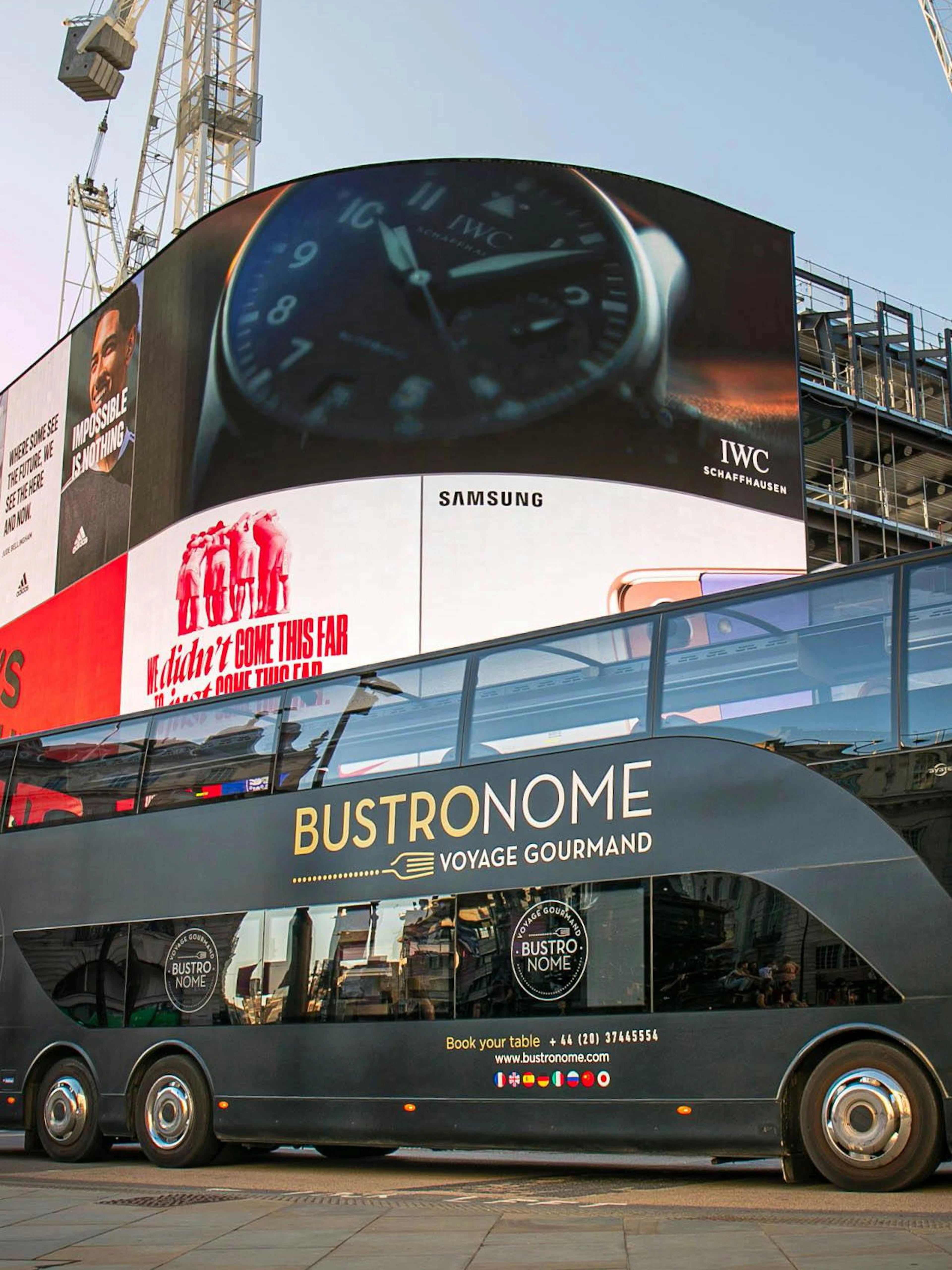 Bustronome tour bus at Piccadilly Circus, London with digital billboards in the background.
