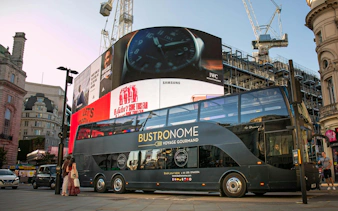 Bustronome tour bus at Piccadilly Circus, London with digital billboards in the background.