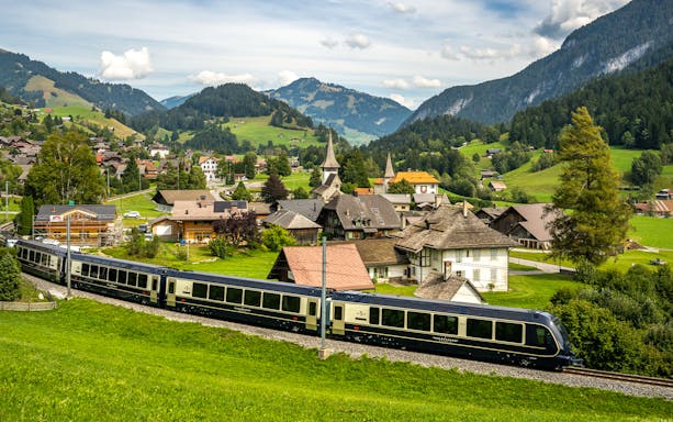 Scenic view of the GoldenPass Express train passing through a Swiss village near Interlaken and Gstaad.
