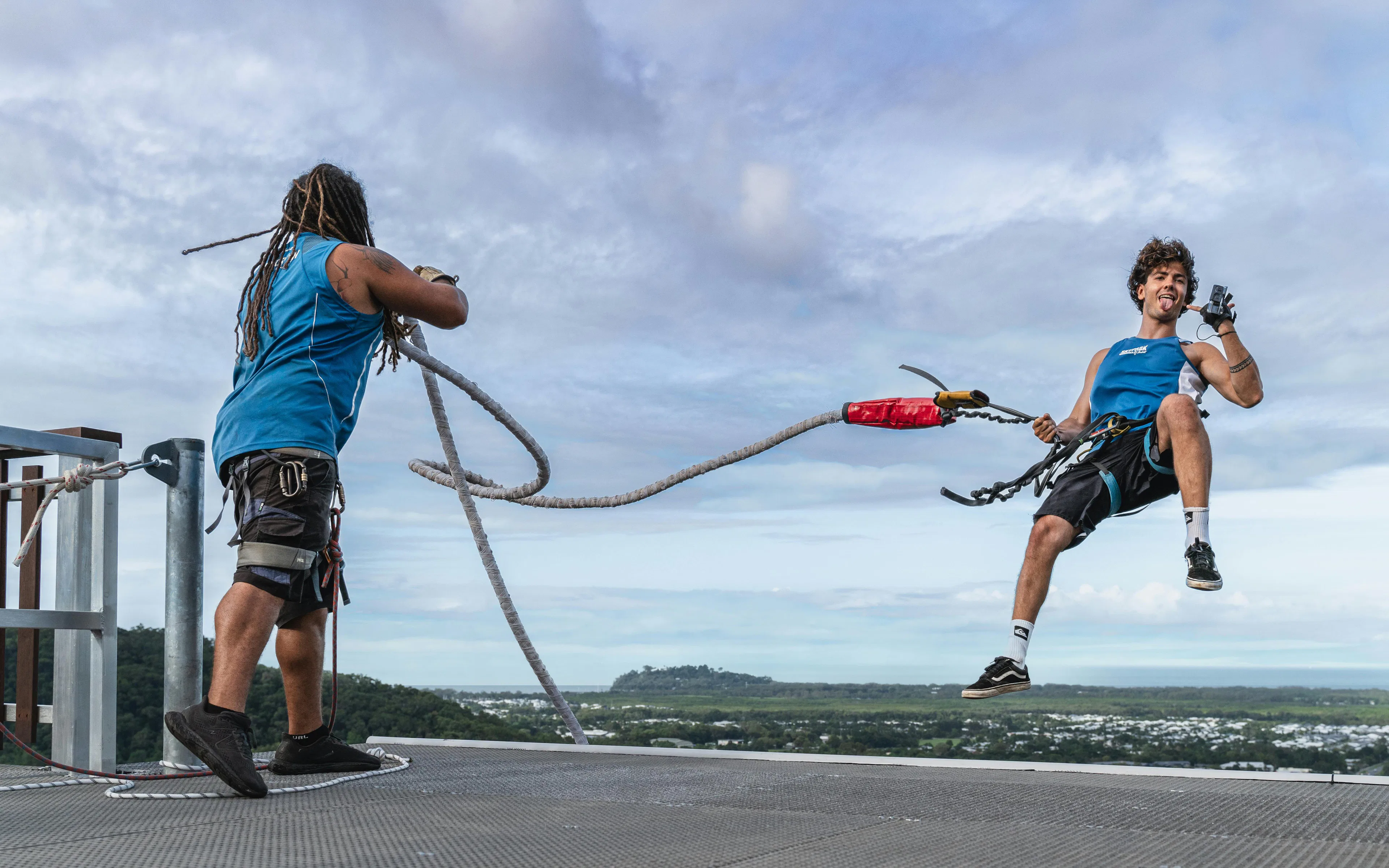 Visitor bungee jumping from Skypark Cairns roof with scenic view in background.
