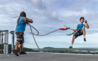 Visitor bungee jumping from Skypark Cairns roof with scenic view in background.