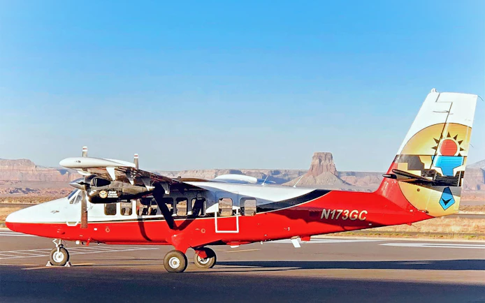 Small airplane on runway with Antelope Canyon and Horseshoe Bend in the background.