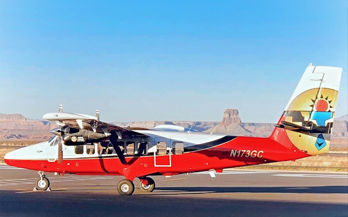 Small airplane on runway with Antelope Canyon and Horseshoe Bend in the background.