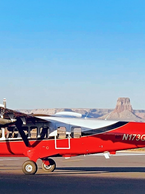 Small airplane on runway with Antelope Canyon and Horseshoe Bend in the background.