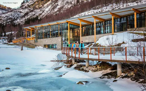 Visitors walking on a snowy path by a modern building in Geiranger during the Ålesund winter fjord cruise.