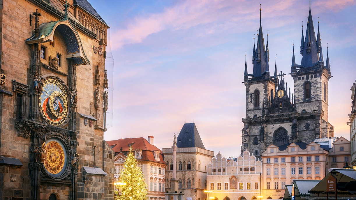 Astronomical Clock Tower in Prague with Tyn Church in the background at sunset.
