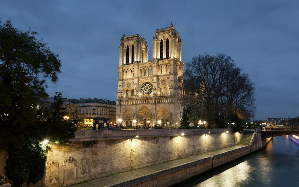 Notre-Dame Cathedral illuminated at night, Paris, near the Seine River.