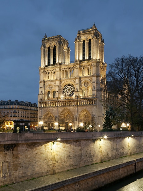 Notre-Dame Cathedral illuminated at night, Paris, near the Seine River.