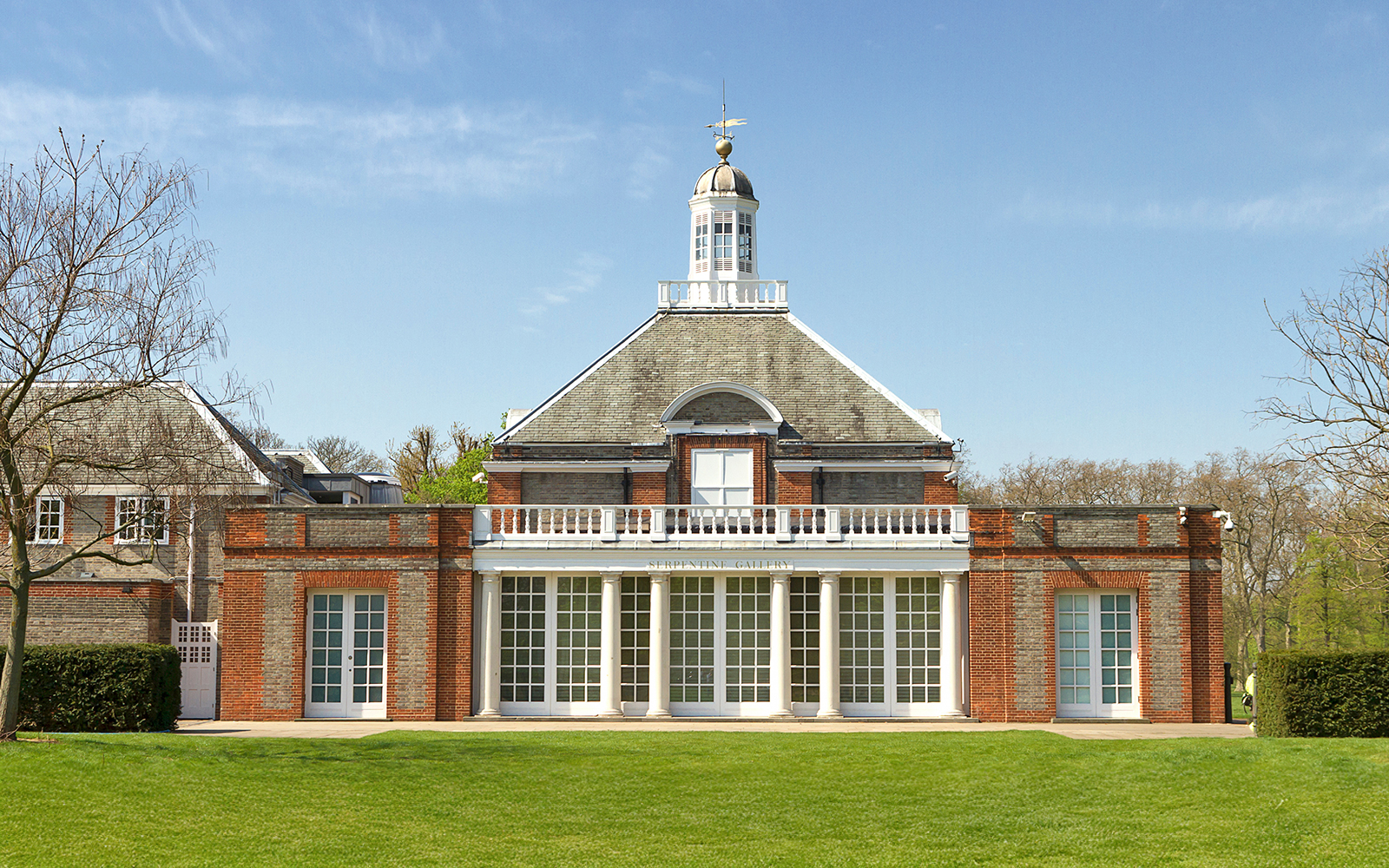 Serpentine Gallery facade in Kensington Gardens, London, with clear blue sky.