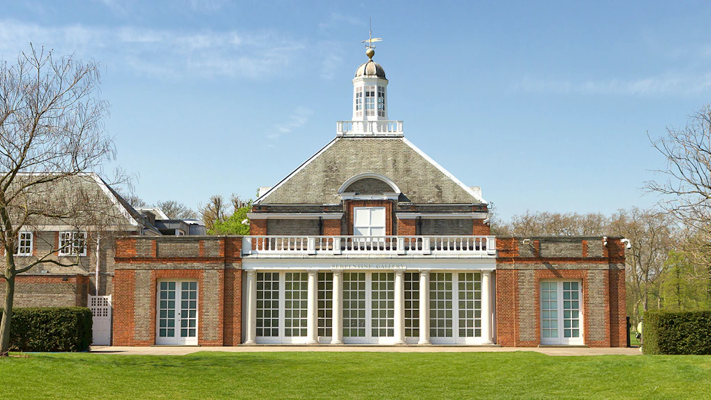 Serpentine Gallery facade in Kensington Gardens, London, with clear blue sky.