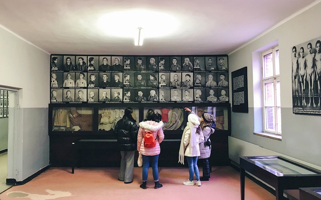 Visitors observing prisoner photos at Auschwitz Birkenau Memorial Museum.