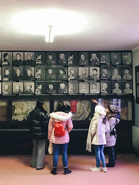 Visitors observing prisoner photos at Auschwitz Birkenau Memorial Museum.