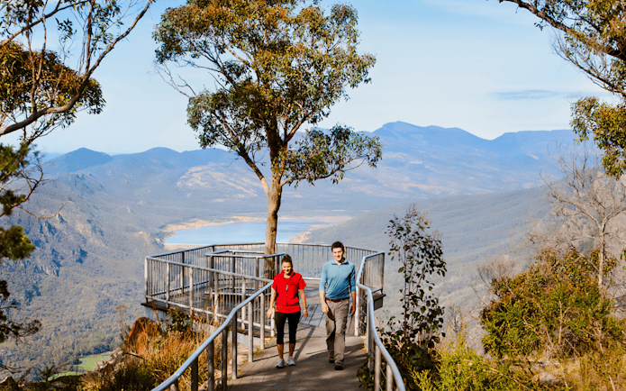 Couple walking on path at Boroka Lookout, Grampians National Park, with mountain view.
