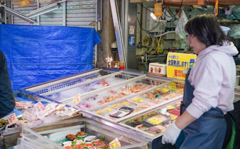 Tsukiji market seafood vendor with fresh fish display, Tokyo tour.