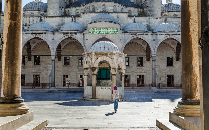 Main entrance courtyard of the Blue Mosque, Istanbul, with a visitor walking.