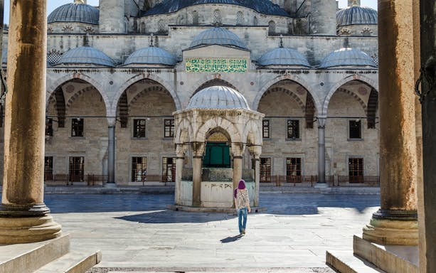 Main entrance courtyard of the Blue Mosque, Istanbul, with a visitor walking.