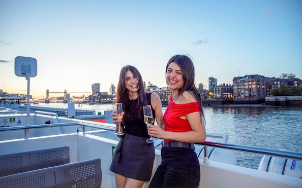 Guests enjoying drinks on a boat deck with a view of Tower Bridge, London.