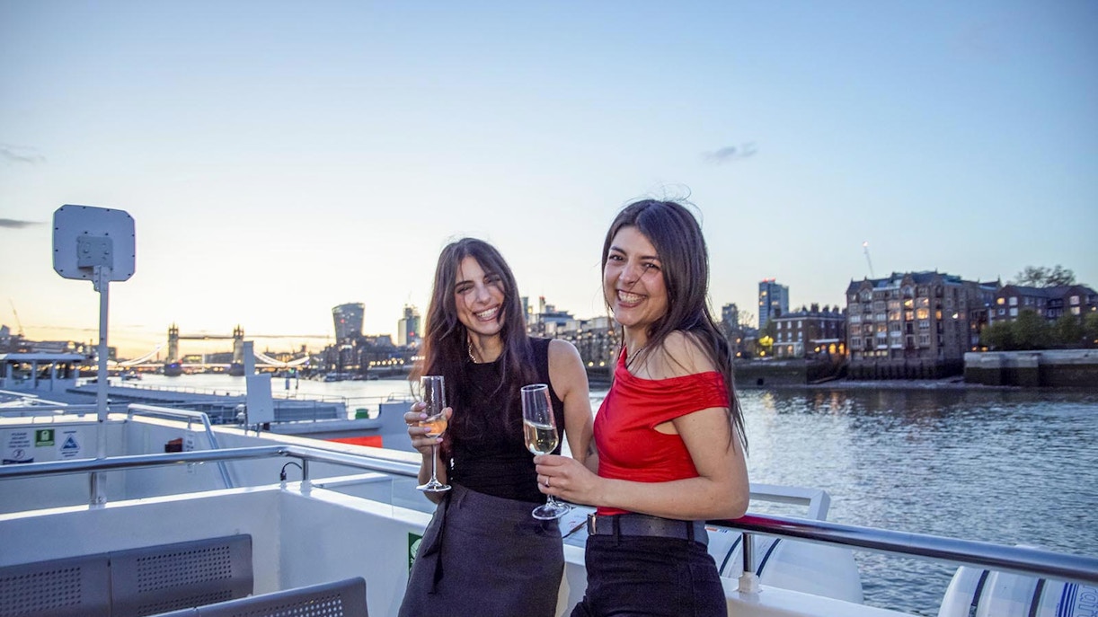 Guests enjoying drinks on a boat deck with a view of Tower Bridge, London.