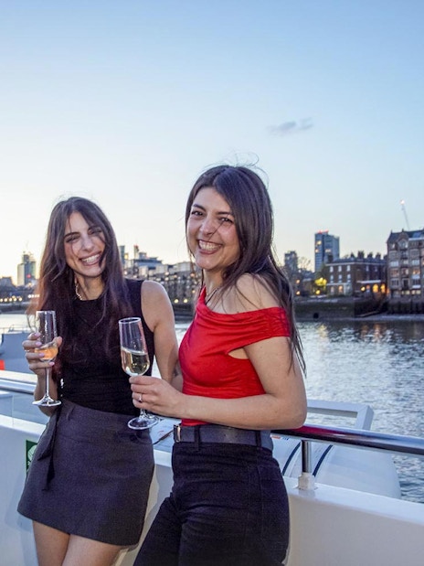 Guests enjoying drinks on a boat deck with a view of Tower Bridge, London.