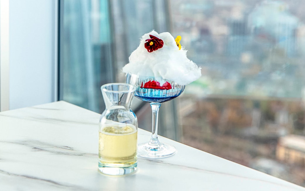 Champagne and dessert on a table with a view from The Shard in London.