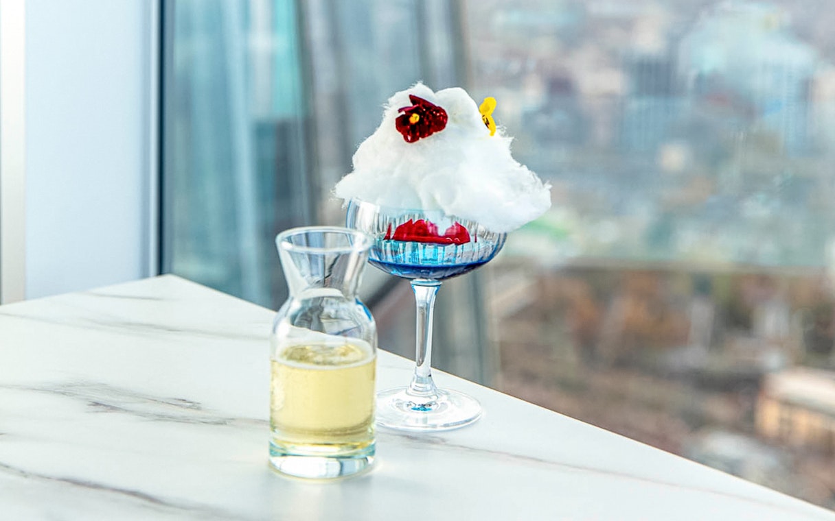 Champagne and dessert on a table with a view from The Shard in London.