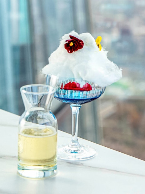 Champagne and dessert on a table with a view from The Shard in London.