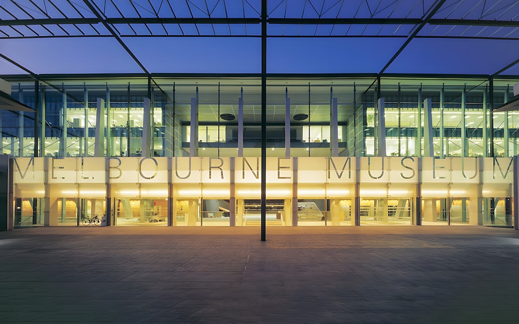 Melbourne Museum entrance illuminated at dusk, showcasing modern architecture.