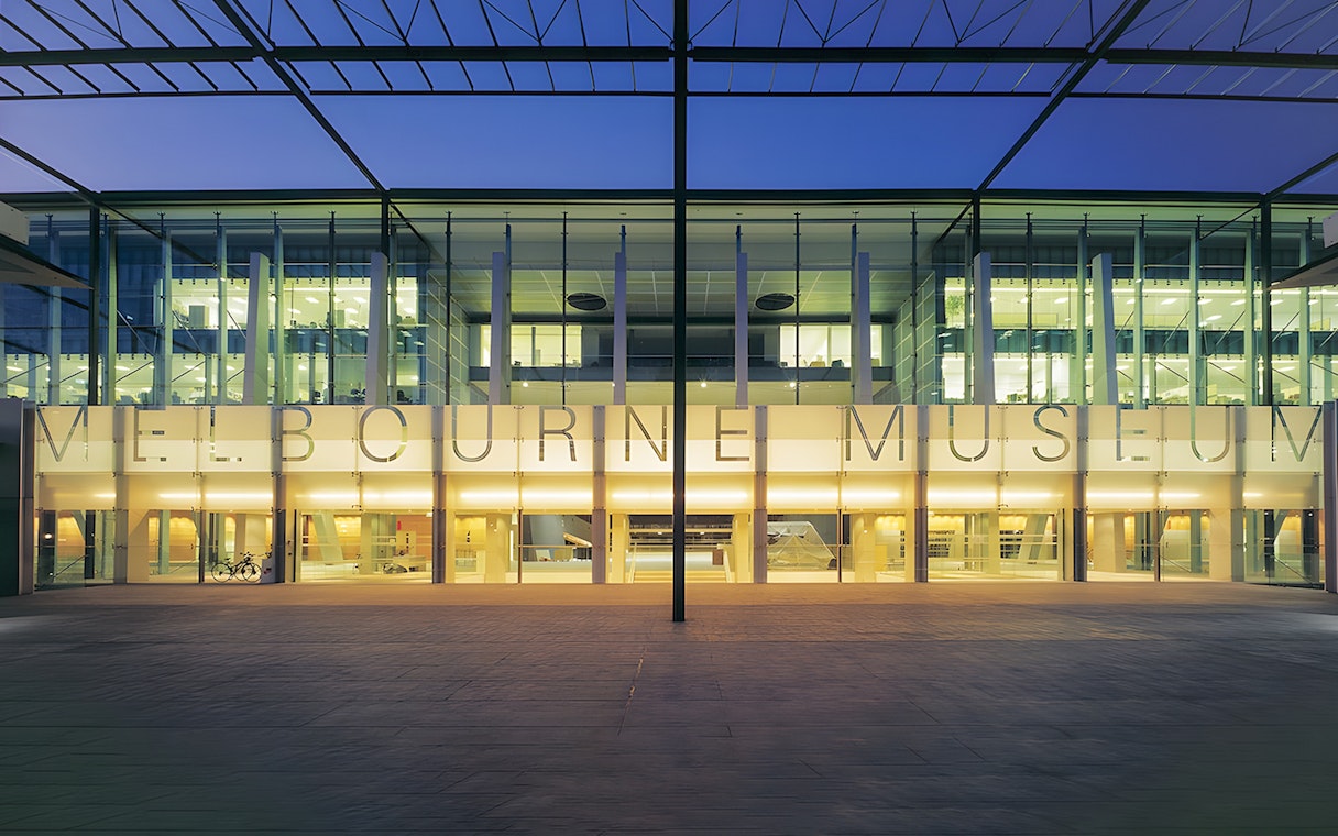 Melbourne Museum entrance illuminated at dusk, showcasing modern architecture.