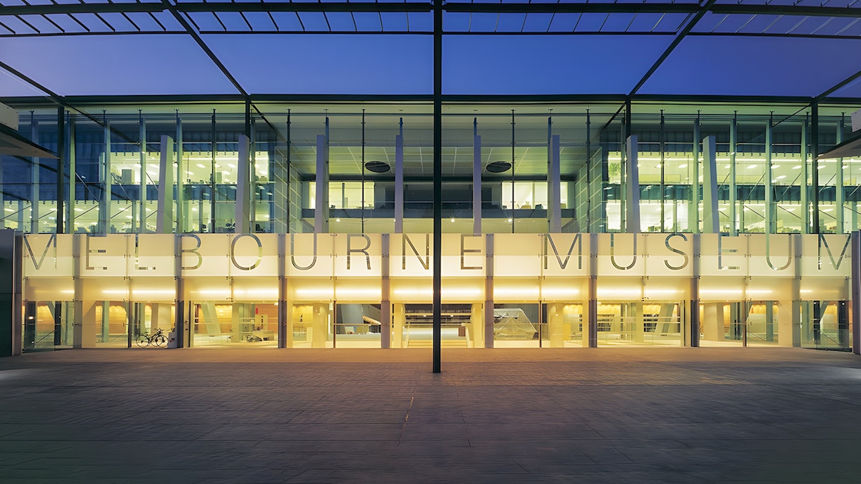 Melbourne Museum entrance illuminated at dusk, showcasing modern architecture.