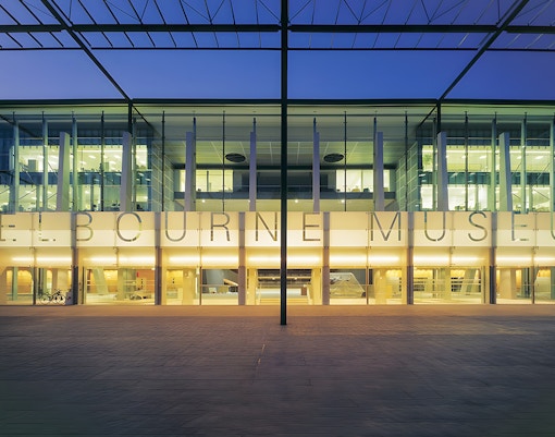 Melbourne Museum entrance illuminated at dusk, showcasing modern architecture.