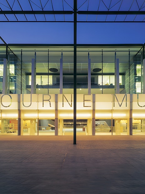 Melbourne Museum entrance illuminated at dusk, showcasing modern architecture.