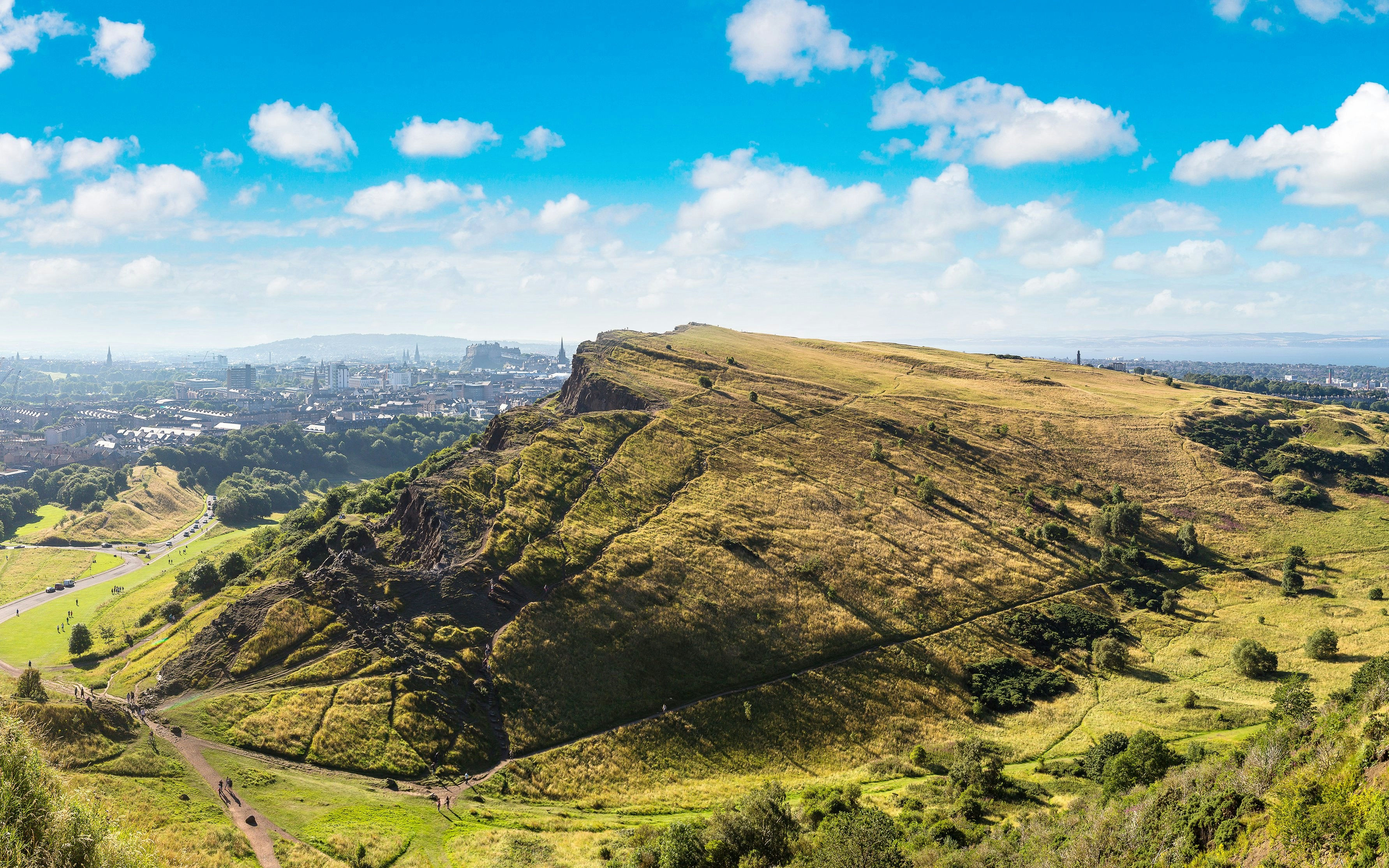 View of Edinburgh cityscape from Arthur's Seat, showcasing rolling hills and historic landmarks.