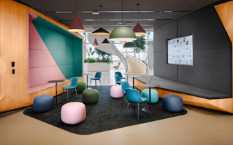 Modern seating area with colorful chairs and poufs at MOL Campus interior.