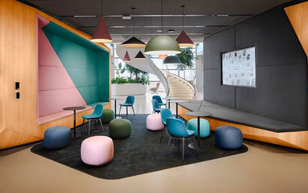 Modern seating area with colorful chairs and poufs at MOL Campus interior.