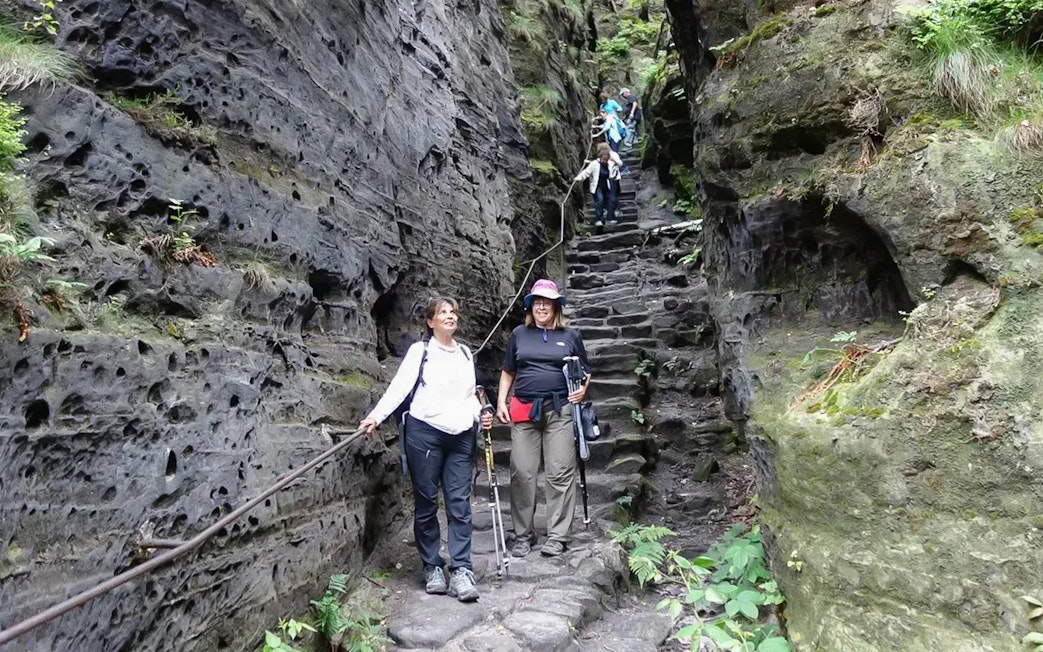 Guests descending stone steps in Tisa Walls Labyrinth, surrounded by rocky cliffs.
