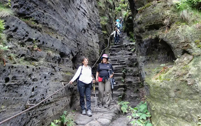 Guests descending stone steps in Tisa Walls Labyrinth, surrounded by rocky cliffs.