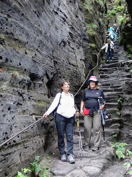 Guests descending stone steps in Tisa Walls Labyrinth, surrounded by rocky cliffs.