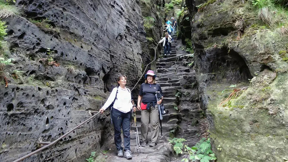 Guests descending stone steps in Tisa Walls Labyrinth, surrounded by rocky cliffs.