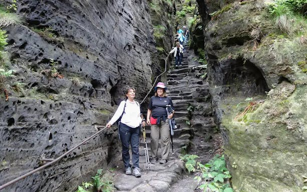 Guests descending stone steps in Tisa Walls Labyrinth, surrounded by rocky cliffs.