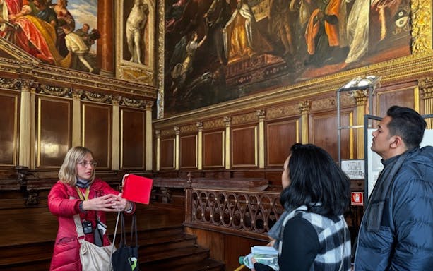 Tour guide explaining artwork to visitors inside Doge's Palace, Venice.